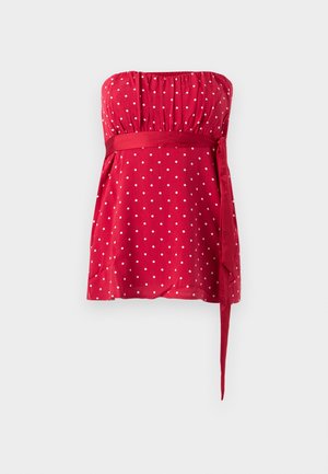 Rode strapless top met witte polka dots, een gerimpeld lijfje en een gestrikte ceintuur die de taille accentueert. Soepele stof met een vloeiend ontwerp.