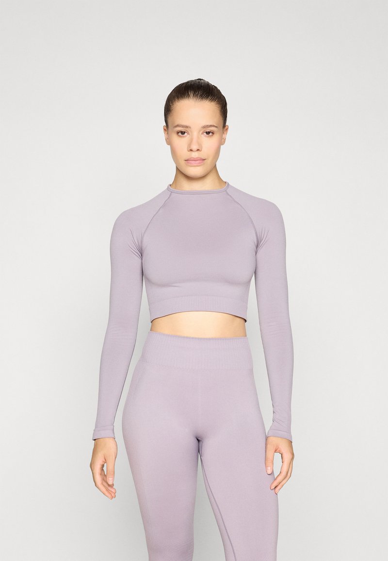 Svijetloplavi dugi crop top s dugim rukavima i odgovarajuće tajice visokog struka. Glatka, rastezljiva tkanina s rebrastim detaljima na manžetama i pojasu.