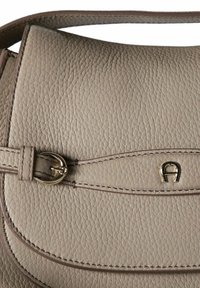 Borsa a mano in pelle beige con finitura texturizzata, dotata di patta curva, dettagli in oro e cuciture decorative. Tracolla regolabile inclusa.