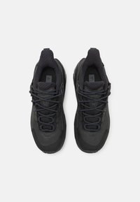 Černé atletické boty s texturovaným materiálem, hladkými syntetickými vrstvami a kulatou špičkou. Obsahují systém šněrování a poutka pro snadné obouvání.