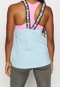 Canotta atletica azzurro chiaro con dettagli rosa e spalline nere con logo. Caratterizzata da una vestibilità comoda e un tessuto traspirante, adatta per allenamenti.