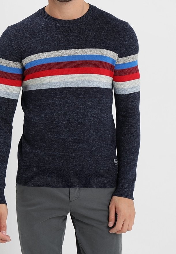 Pull en tricot bleu marine à manches longues, avec des rayures horizontales rouges, bleues, grises et blanches sur la poitrine. Coupe régulière.