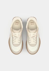 Sneaker crema e beige con una tomaia testurizzata, caratterizzata da una suola in gomma, design con lacci e marchio "BOSS Ortholite" sulla linguetta.