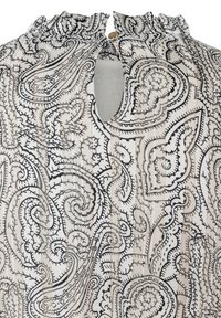 Jasna bluzka z czarnym wzorem paisley na kremowym tle, z falbanistym dekoltem i otworem w kształcie łezki z guzikiem.