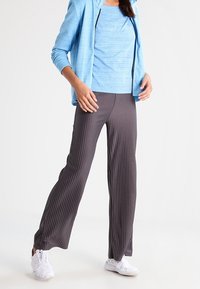 Gray ribbed pants paired with a light blue top and a blue jacket, featuring a relaxed fit and white sneakers.