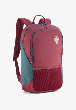 Sac à dos rouge et bleu sarcelle avec poches en mesh à l'avant, logo Puma et écusson de l'équipe de football du Portugal, avec bretelles rembourrées et double fermeture éclair.
