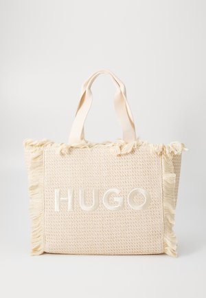 Bolso tote tejido en crema con bordes deshilachados y el logotipo en relieve "HUGO" en el centro. Presenta asas de tela resistentes para un fácil transporte.