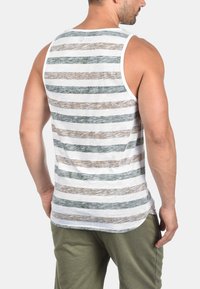 Stripet tanktopp i grått, hvitt og brunt. Har en avslappet passform, rund hals og mykt, teksturert stoff.