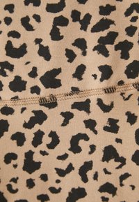 Beige stof met een zwart luipaardpatroon. Bevat onregelmatige vormen en een gladde textuur, met contrasterende stiksels langs één naad.