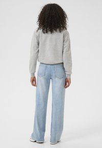 Grauer Sweatshirt mit Rundhalsausschnitt, kombiniert mit hellblauen weit geschnittenen Jeans mit Gesäßtaschen. Weicher Stoff und lässiges Design.