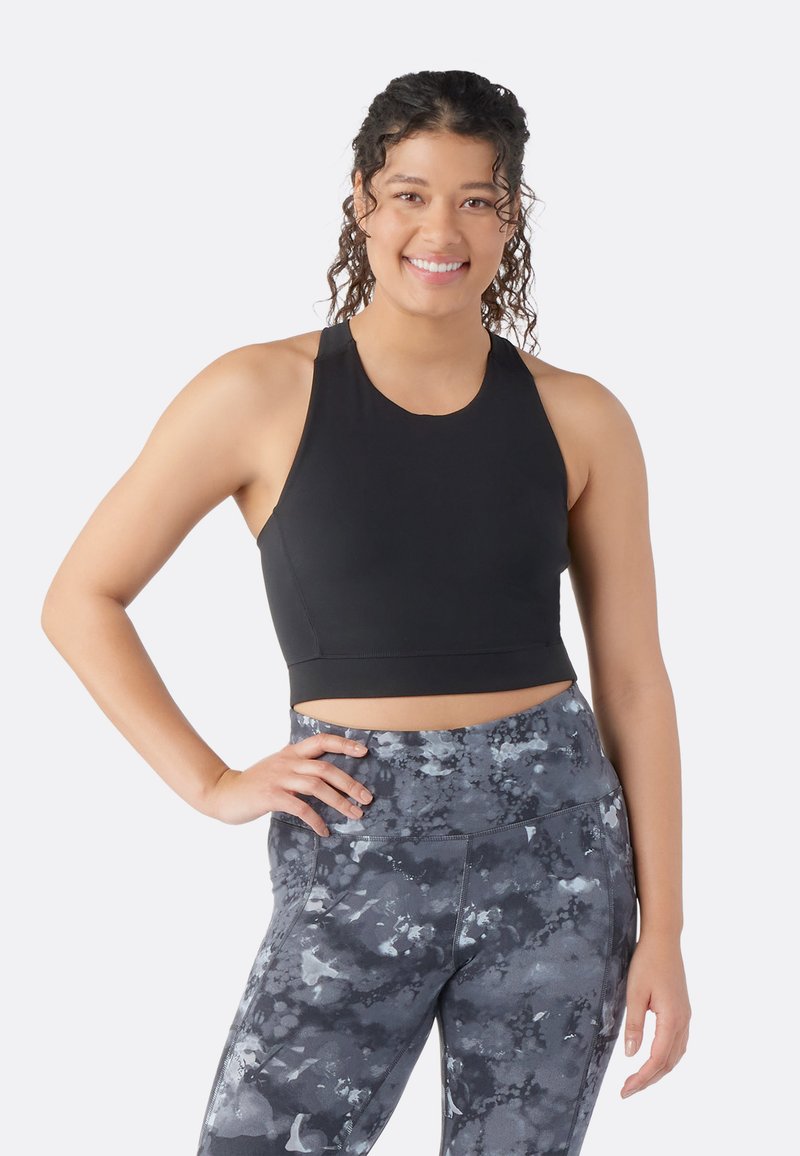 Top corto atlético negro con tirantes anchos, combinado con leggings de talle alto que presentan un patrón abstracto en gris y negro.