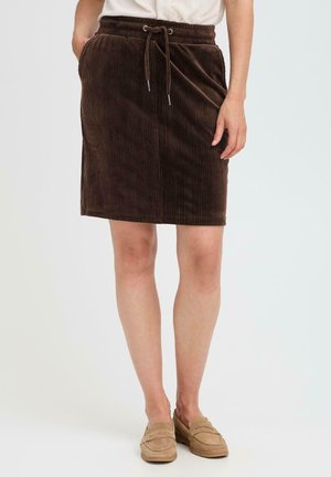 Brun kordfløyelskjørt med strammingslinning, kne-lengde, med vertikale linjer og en myk tekstur. Kombinert med beige slip-on sko.