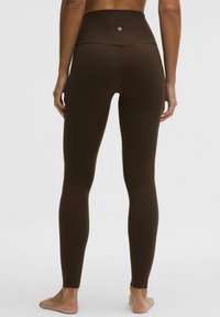 Leggings marrones de cintura alta con un acabado suave, ajuste ceñido y detalles de costuras mínimas. Cuenta con un pequeño logotipo en la parte trasera de la cinturilla.