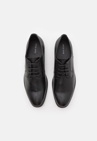 Scarpe in pelle nera con finitura liscia, punta arrotondata e cuciture sottili. Presentano un design con lacci e una suola in gomma resistente.