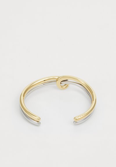 Bracelet en métal doré et argenté avec un design torsadé au centre. Fini lisse et brillant ; sa forme à bout ouvert améliore l'ajustabilité.