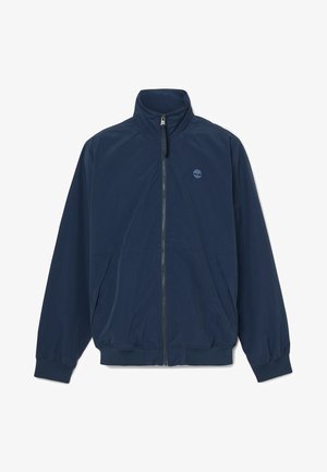 Granatowa, lekka kurtka wykonana z gładkiego materiału, z wysokim kołnierzem, pełnym zamkiem, elastycznymi mankietami i emblematem logo na klatce piersiowej.