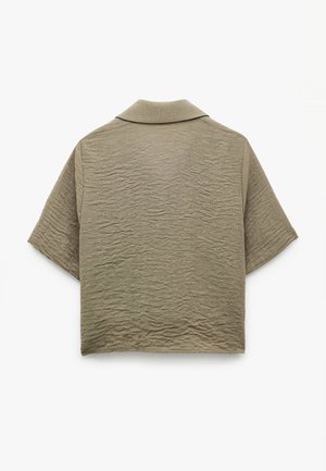 Lyhythihainen, kauluksellinen paita oliivinvihreänä, jossa on rakennekuvioinen, rypistynyt kangas. Takapäin näkyy rento istuvuus ja minimalistinen muotoilu.