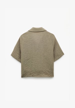 Lyhythihainen, kauluksellinen paita oliivinvihreänä, jossa on rakennekuvioinen, rypistynyt kangas. Takapäin näkyy rento istuvuus ja minimalistinen muotoilu.