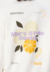 Sudadera blanca con un diseño gráfico de frutas estilizadas, incluyendo naranja y limón, con texto multicolor: "Marc O'Polo Denim."