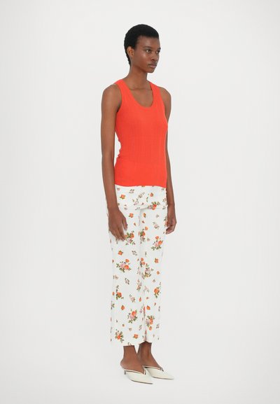 Rød stripete tanktop kombinert med blomstrede hvite bukser og lyse spisse mules. Glatt tekstur, tettsittende design og ankellange bukser.