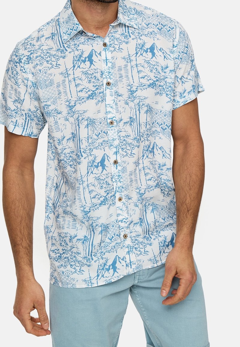 Korte mouwen shirt van lichtblauwe stof met een boom- en bergpatroon, voorzien van bruine knopen en een relaxed fit.