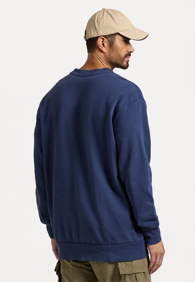 Sweatshirt azul-marinho feito de tecido suave, com um clássico decote redondo, mangas longas e um corte descontraído. A vista traseira mostra um detalhamento mínimo.
