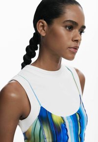 Top fără mâneci, realizat dintr-o țesătură de bumbac alb, cu un overlay cu modele albastre și verzi. Textură netedă și decolteu rotund.