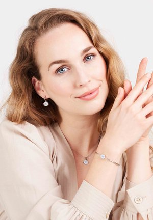 Zilveren sieradenset bestaande uit een hangerketting en armband, elk met ronde bedels, tegen een neutrale achtergrond.