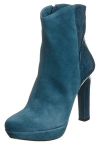 Teal suede ankle boot with a glossy panel on the side, high stiletto heel, rounded toe, and a smooth texture. Features a zip closure.