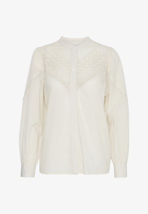 Camicia bianca con bottoni frontali, tessuto testurizzato, dettagli in pizzo sulle spalle e maniche lunghe a sbuffo. Presenta un colletto alla mandarino e motivi sottili.