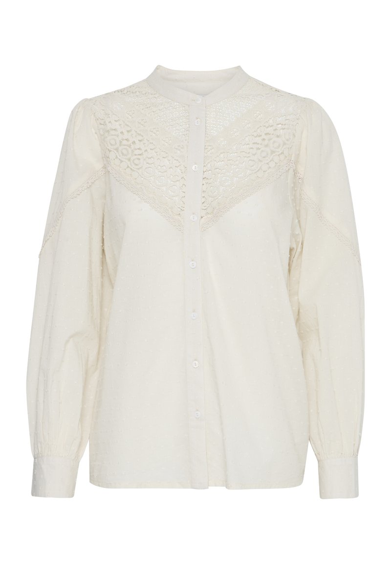 Camicia bianca con bottoni frontali, tessuto testurizzato, dettagli in pizzo sulle spalle e maniche lunghe a sbuffo. Presenta un colletto alla mandarino e motivi sottili.