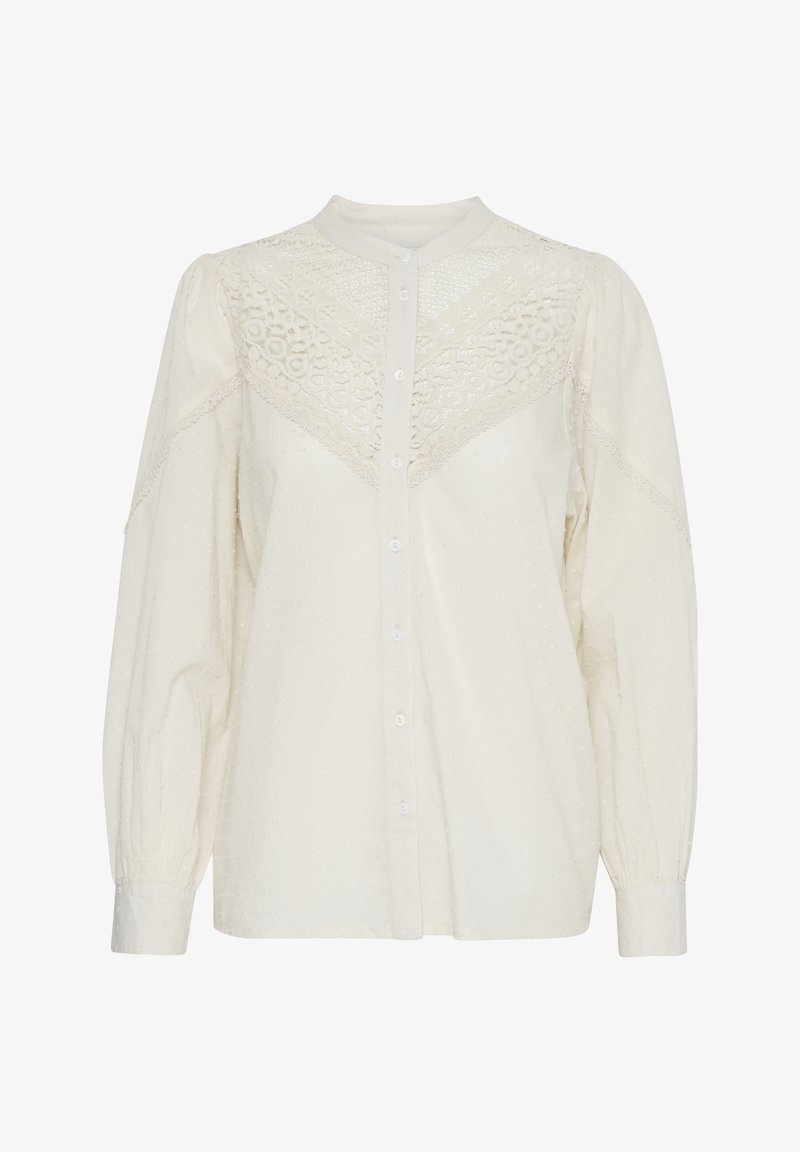 Camicia bianca con bottoni frontali, tessuto testurizzato, dettagli in pizzo sulle spalle e maniche lunghe a sbuffo. Presenta un colletto alla mandarino e motivi sottili.