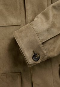 Khaki sulejope, millel on nööbita cuff ja kaks esikot. Kanga pind on pehme ja tekstureeritud.