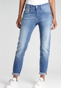 Hoch taillierte, hellblaue Jeans aus Denim mit schmalem Schnitt, ausgestattet mit Vordertaschen und umgeschlagenen Säumen. Leichte Ausbleichungen und Nähdetails vorhanden.