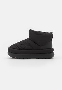 Botas tobilleras negras y acolchadas con punta redonda, hechas de tejido acolchado y suela de goma, con un talón elevado y fondo texturizado para mayor agarre.
