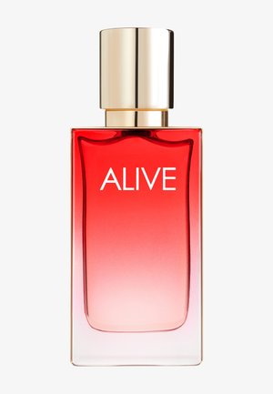 Botella de perfume rectangular con degradado rojo etiquetada "ALIVE" con un tapón dorado brillante sobre un fondo claro.
