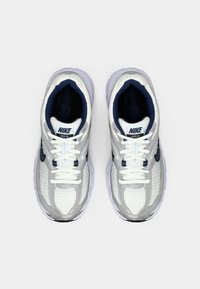Białe siateczkowe sneakersy sportowe z szarymi akcentami, granatowym wnętrzem i białymi sznurówkami. Posiadają amortyzowaną podeszwę oraz logo Nike na języku.