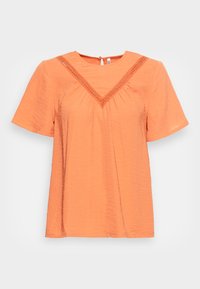 Top de mangas curtas, solto, em laranja claro, com decote em V, decorado com detalhe de renda ao longo da borda. Tecido simples e texturizado.