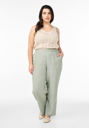 Beige strikket tanktop med et geometrisk mønster, parret med lysegrønne, vide bukser med sidelommer. Sko i neutrale nuancer fuldender outfittet.