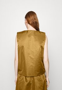 Brown sleeveless top with a smooth, shiny texture, featuring a round neckline and a relaxed fit. The back is plain with no visible closures.