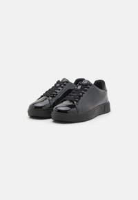 Schwarze Sneaker mit glänzender Oberfläche, runder Zehenpartie, Schnürung vorne und strukturiertem Gummiboden. Glattes Obermaterial ohne Muster oder Akzente.