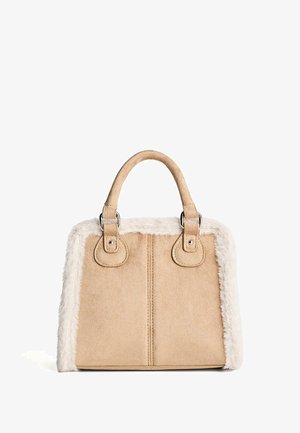 Beigefarbene Wildlederhandtasche mit zwei abgerundeten Griffen und weißem, flauschigem Besatz entlang der Kanten, vor weißem Hintergrund gezeigt.