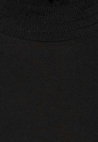 Svart bomulls-t-shirt med ribbad rund halsringning. Tyget har en slät yta med lätt stretch, vilket ger en figurnära passform.