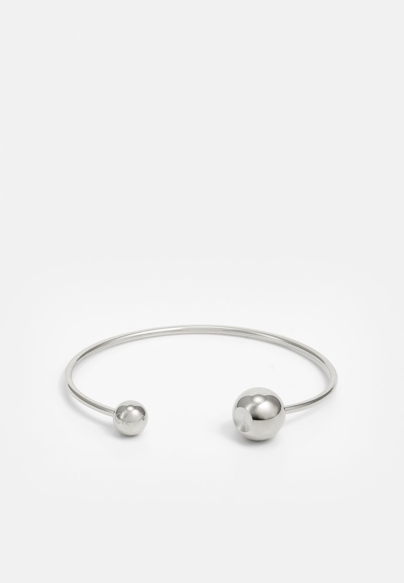 Brazalete de metal plateado con dos acentos esféricos en cada extremo, superficie lisa, diseño abierto y forma elegante y minimalista.