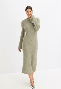 Abito midi in maglia verde chiaro con finitura texturizzata, maniche lunghe e vestibilità rilassata. Presenta un collo a giro e spacchi laterali all'orlo.