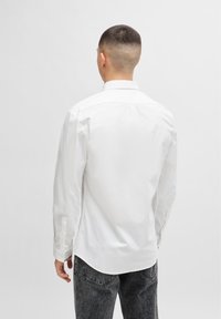 Witte langemouwen shirt met een button-down kraag, gemaakt van katoen, met een gebogen zoom en knoopmanchetten. Draagt het met donkere jeans.
