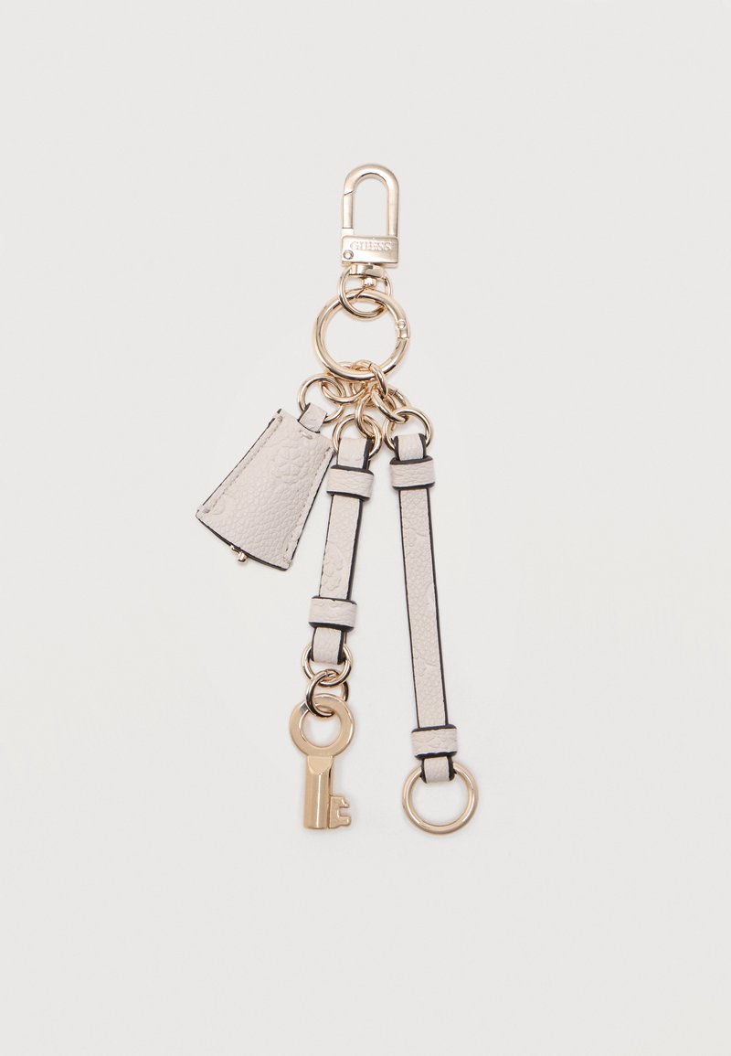 Μπρελόκ με χρυσό κούμπωμα, δύο λευκά δερμάτινα λουράκια, μικρή λευκή υφασμένη ετικέτα και χρυσό διακοσμητικό κλειδί σε απλό φόντο.