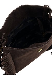 Brązowa zamszowa torebka z frędzlami, otwarta, ukazująca ciemne wnętrze wyłożone materiałem z logo marki, z kieszenią na zamek i złotymi okuciami.