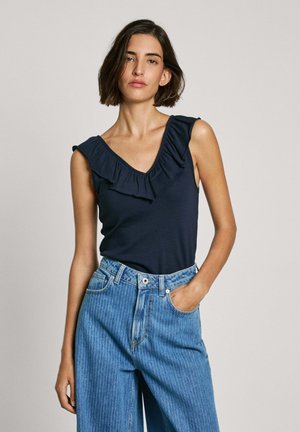 Marineblauw mouwloos topje met een V-hals en ruches. Gecombineerd met lichtblauwe, wijde gestreepte denim jeans.