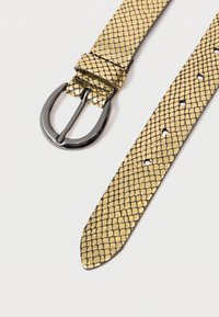 Kultaiset käärmeennahkavyö, jossa on sileä pinta, musta metallisuuskiinnitys ja useita säädettäviä reikiä hihnassa.